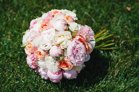 美丽的花束从盛开的牡丹和玫瑰的壮丽花朵躺在绿草特写婚礼当图片