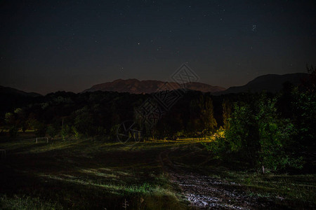 美丽的夜景与星夜山和森林有绿色草甸和山的夜森林在明亮的星夜图片