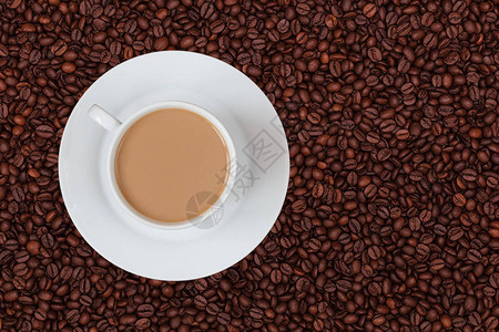 咖啡豆背景上的一杯白牛奶咖啡图片