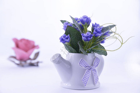 蓝色花朵在一个陶瓷茶壶里用粉红玫瑰图片