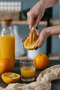 用木制榨汁机制作新鲜橙汁的女人图片