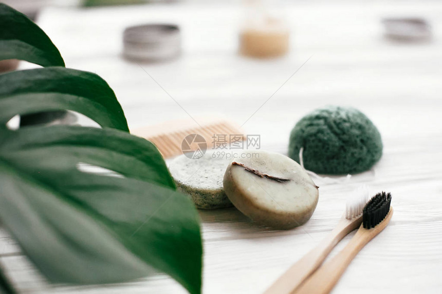 天然竹牙刷洗发水棒玻璃中的牙膏木笔刷和白木底的Konjaku海绵图片