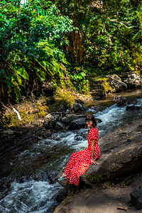 在巴厘岛雨林深处的山河上穿着长红色裙图片