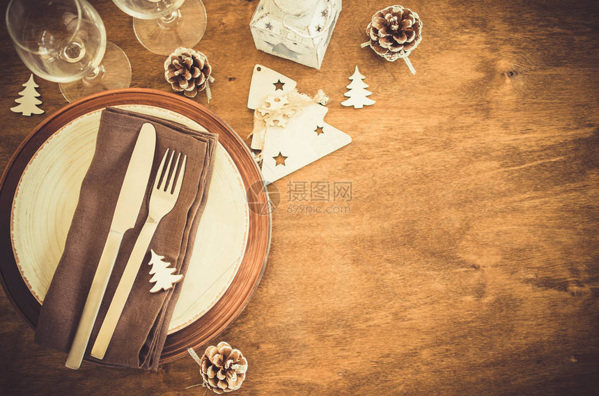 简单的圣诞餐桌位设置在复古或乡村风格的木制为圣诞节或晚餐设图片