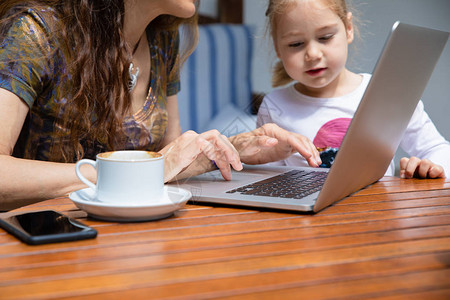 四岁的女孩看着女人的手在pc笔记本电脑的键盘上打字图片