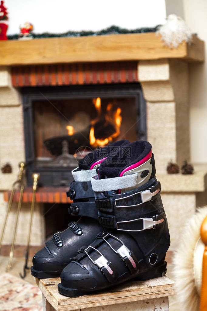 在壁炉前晒鞋两双滑雪靴站在明亮的房间里燃烧的壁图片