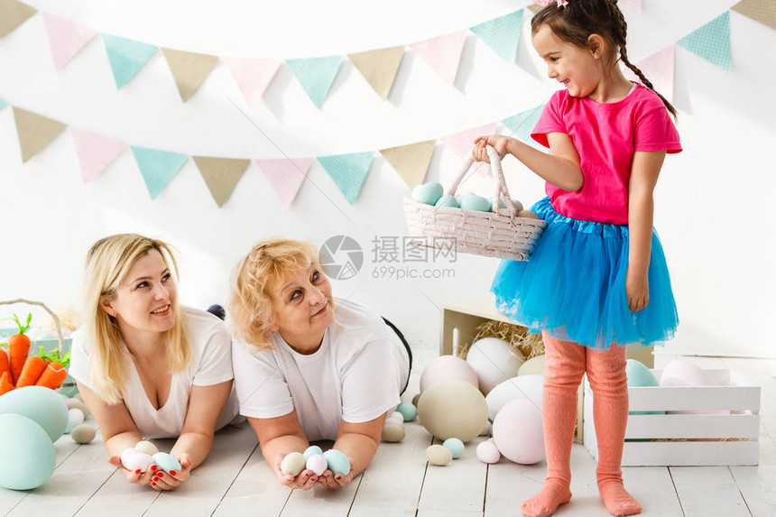 快乐的小女孩与母亲和祖母玩复活节鸡蛋图片