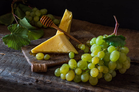 豪达马斯达姆切达干酪和木头上的葡萄图片