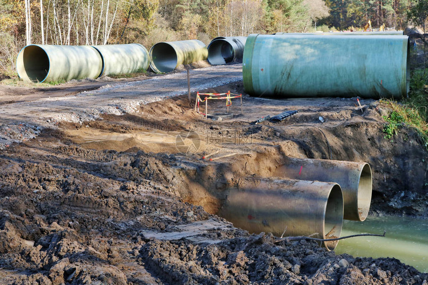 大型下水道管位于秋天森林建筑工地的沙土和上图片