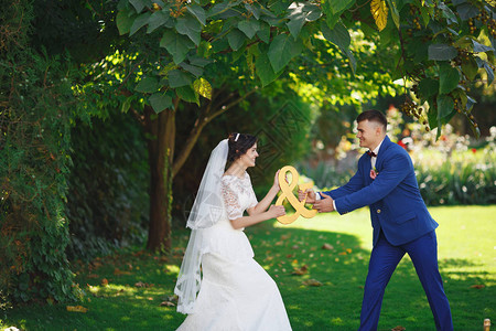 刚结婚的爱时髦夫妇穿着婚纱和西装在公园里幸福的新娘和新郎走在美丽的花园里浪漫的已婚年轻家背景图片