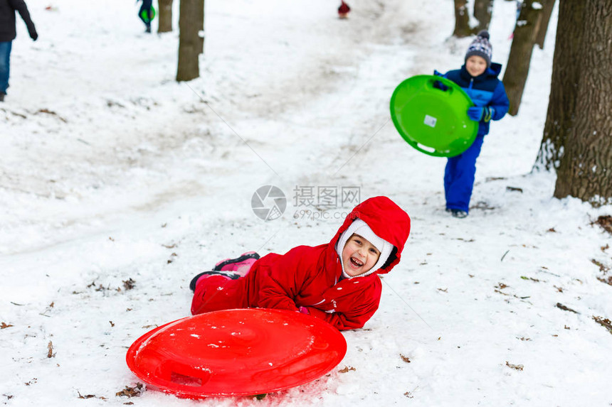 穿着滑雪西装的笑着小女孩滑下一个小雪地图片