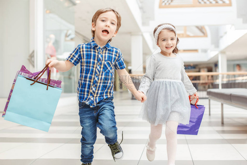 两个可爱的学龄前儿童去购物的集体肖像白种人小女孩和男孩在商场里奔跑孩子们拿着购物袋黑色星图片