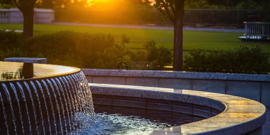 日落时有反射水的室外喷泉日落时有多个水流的室外喷泉景观在背景中可以看到有树木和植图片