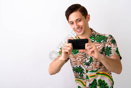摄影工作室拍摄年轻快乐的旅游男子在白色背景下用手机拍照时笑图片