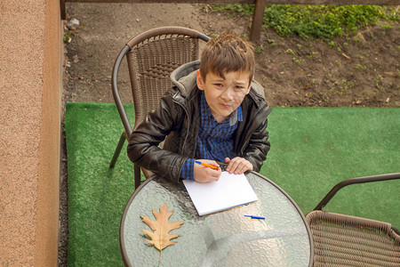 男孩正在写东西男孩在户外做作业男孩在纸图片