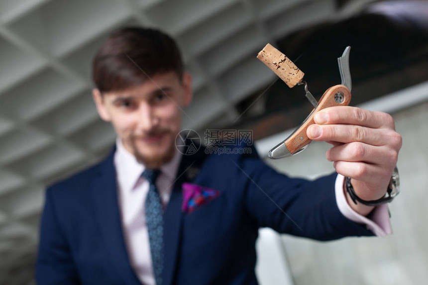 一个年轻男人在餐厅里喝葡萄酒时拿着一个索梅利的cor图片