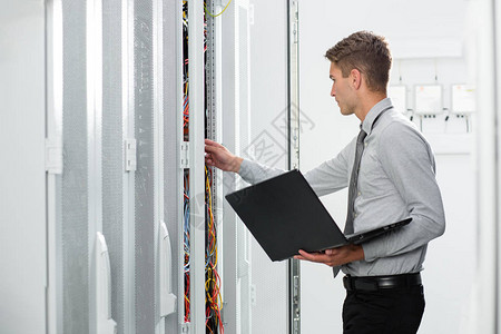 青年男子在服务器柜中连接电线图片