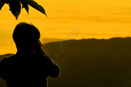 享受在山上拍摄日落的人剪影图片