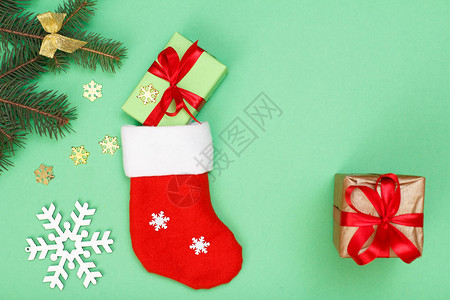 圣诞装饰圣诞老人的靴子礼品盒冷杉树枝和绿色背景上的雪花顶视图图片