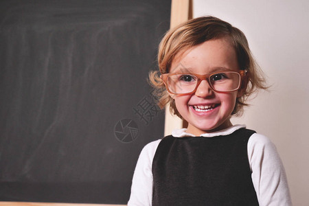一个快乐的小女孩打扮成小黑板前的老师图片