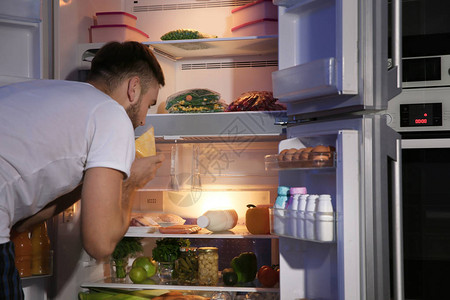 年轻人晚上在冰箱里找食物图片