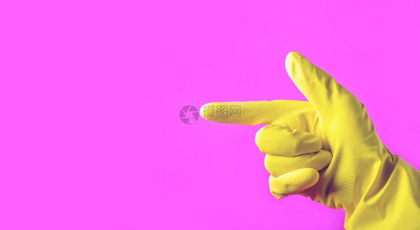 手和黄色橡胶手套指着侧面的粉红色背景清洁概图片