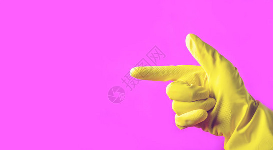 手和黄色橡胶手套指着侧面的粉红色背景清洁概图片