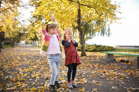 秋天公园里玩树叶的可爱小女孩图片