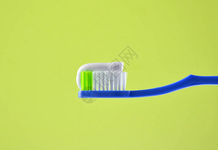 蓝色光背景上粉红色牙刷上的牙膏特写背景图片