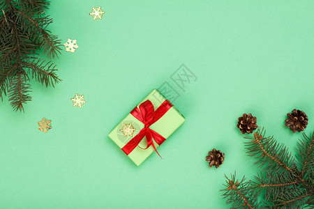 圣诞装饰礼品盒带锥体的冷杉树枝和绿色背景上的装饰雪花顶视图图片