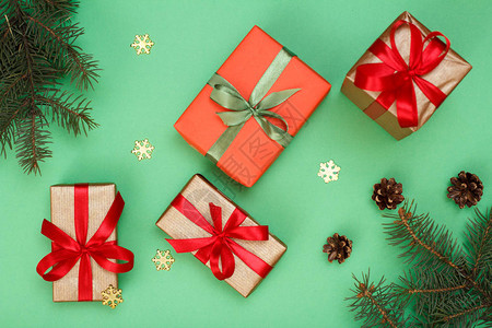 圣诞装饰礼品盒带锥体的冷杉树枝和绿色背景上的装饰雪花顶视图图片
