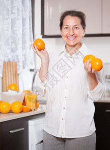 笑着的中年妇女在厨图片