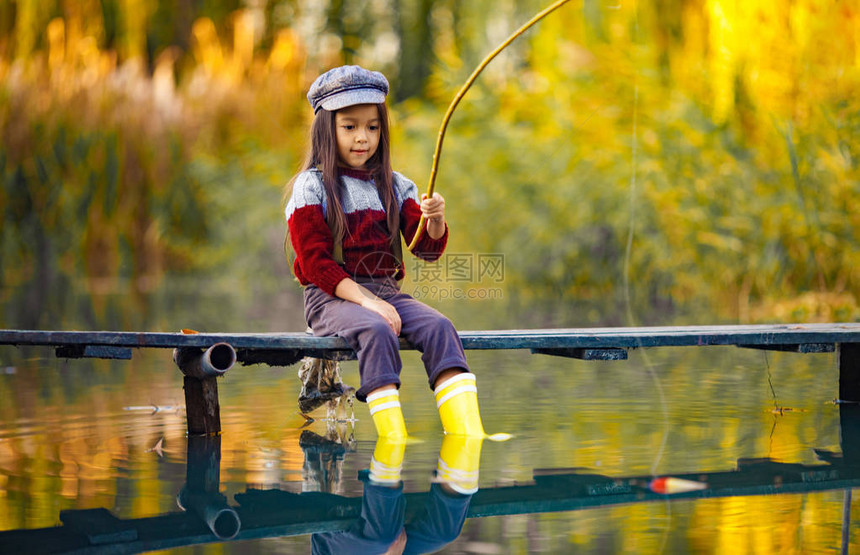 女童坐在木制捕鱼桥上在秋天用图片