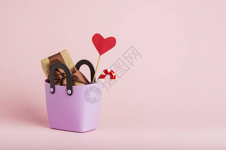 用于购物的小塑料袋礼品盒棍子上的心粉红色的背景图片