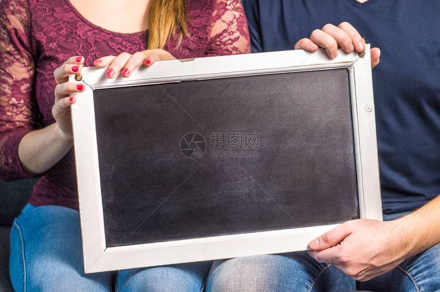 人拿着带木框的空黑板朋友或一对夫妇显示空白黑板与背景的副本空间学生学校或企业的工作人员设计图片