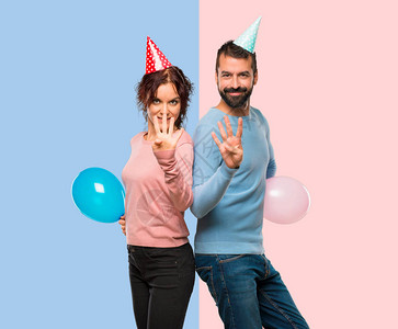 一对夫妇的气球和生日帽子快乐数到四手指在粉色图片