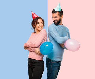 双对配有气球和生日帽子的情侣仰望着肩膀微笑在粉色图片