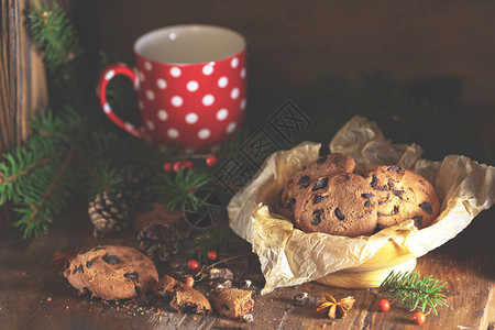 圣诞节和新年组成与美味的巧克力饼干花生和一杯咖啡或茶云杉树枝和松果在图片