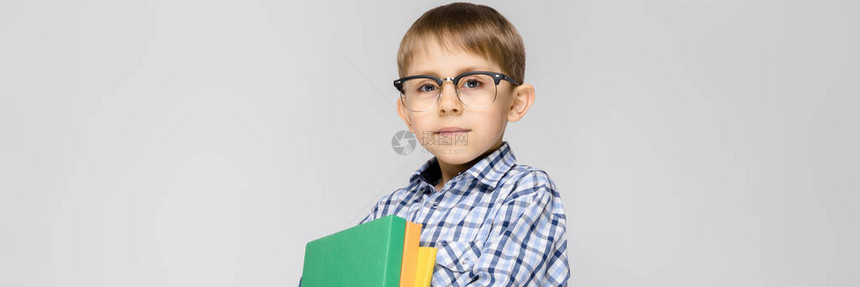 一个男孩在灰色背景上的肖像一个戴眼镜的男孩男孩拿图片