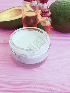 粉红色木质背景中的化妆品霜鳄梨油图片