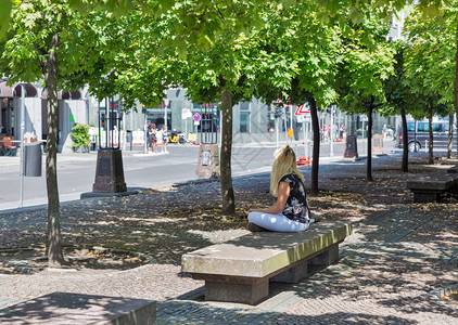 在阳光明媚的日子坐在城市公园的石板上的未经承图片