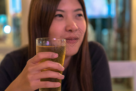 参加幸福行动在酒吧和餐馆喝啤酒的亚洲年轻女低光放松与饮酒概图片