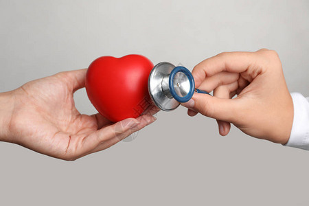 医生把听诊器放在玩具心脏附近的病人手上图片
