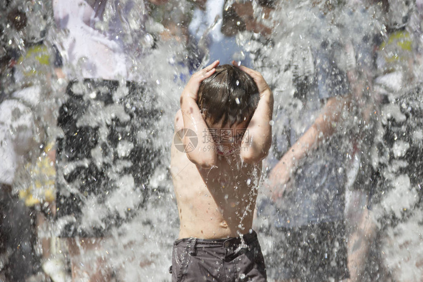 水射流下的小男孩子在喷泉里洗澡雨中的人图片