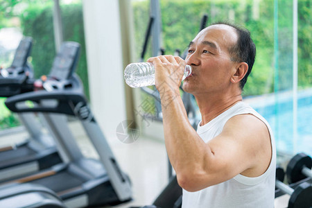 老人锻炼后在健身中心饮用矿泉水老年人健康生活方式请查看InfoFin图片