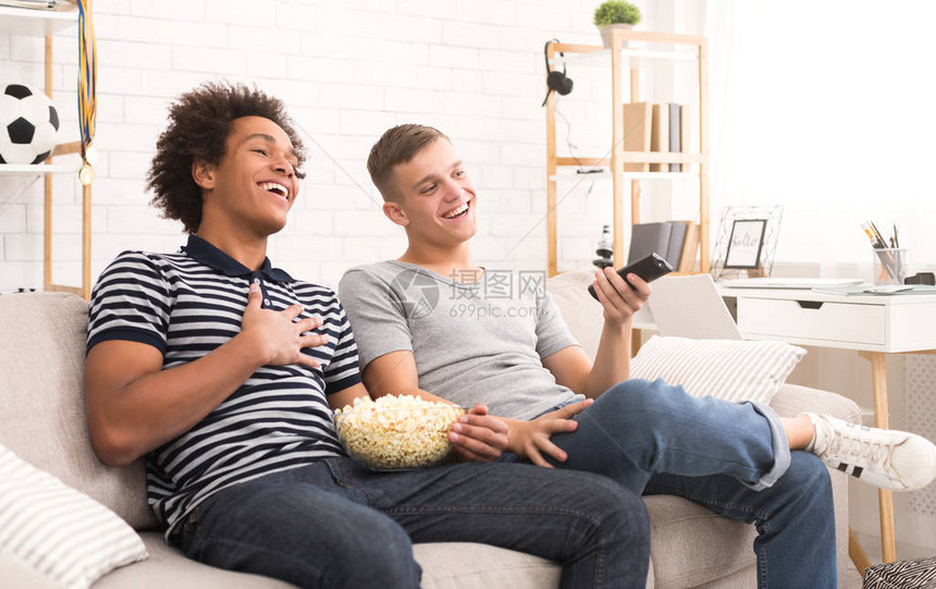 两个快乐的青少年家伙在电视上看喜剧电影在家里吃爆米图片