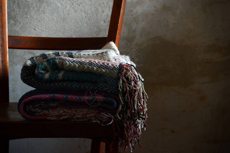 水泥墙附近的旧椅子和一堆温暖的羊毛毯图片