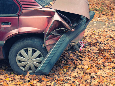 碰撞事故后汽车的后部破碎的皱巴的后保险杠和爆胎的特写侧拍秋天的季节铺图片