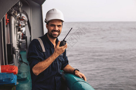 船舶或船舶甲板上的海事甲板高级船员或大副他手里拿着甚高频对讲图片