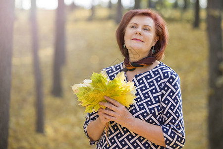 五十岁的妇女在公园里有秋图片